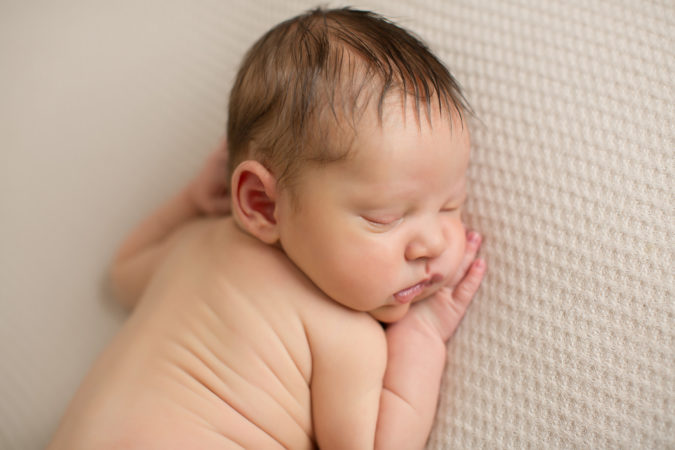 Newborn boy laying on cream backdrop taken by DMV photographer Sarah Botta Photography