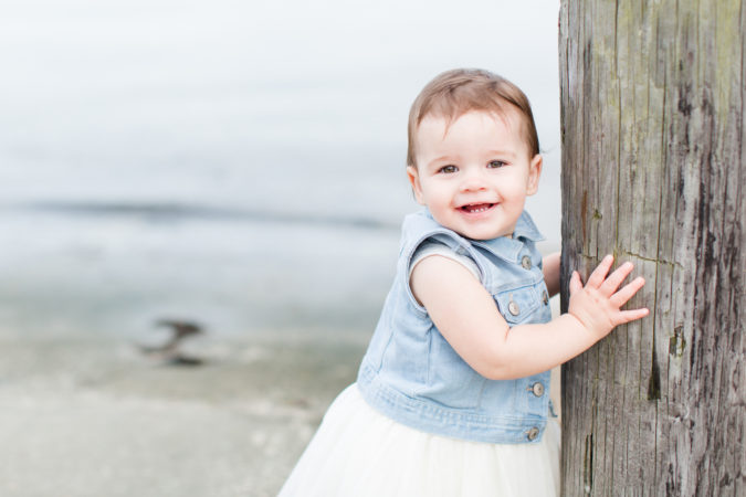 1 Year old girl smiling and holding on to post in New Jersey by Virginia photographer Sarah Botta Photography