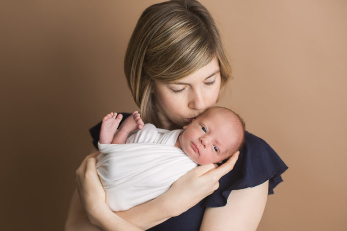 Mom holding newborn boy in white wrap with Woodbridge Studio Newborn session with Sarah Botta Photography