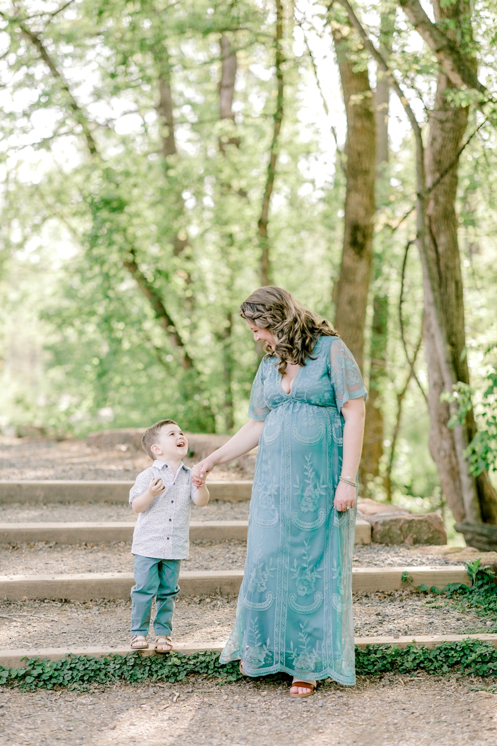 Maternity session outdoors with Sarah Botta Photography. Pregnant mother holding young sons hand walking down outdoor stairs surrounded by stairs.